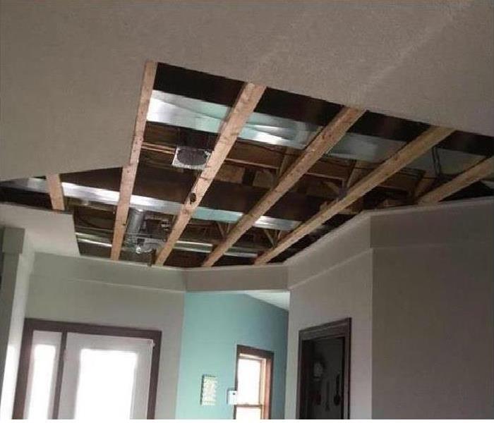 A ceiling has drywall removed after storm damage caused a roof to leak.