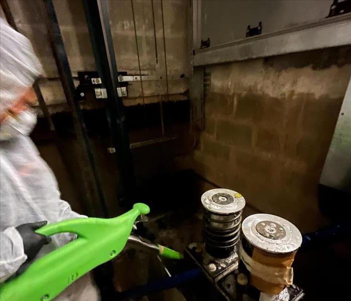 SERVPRO technician is cleaning up water damage in an elevator well